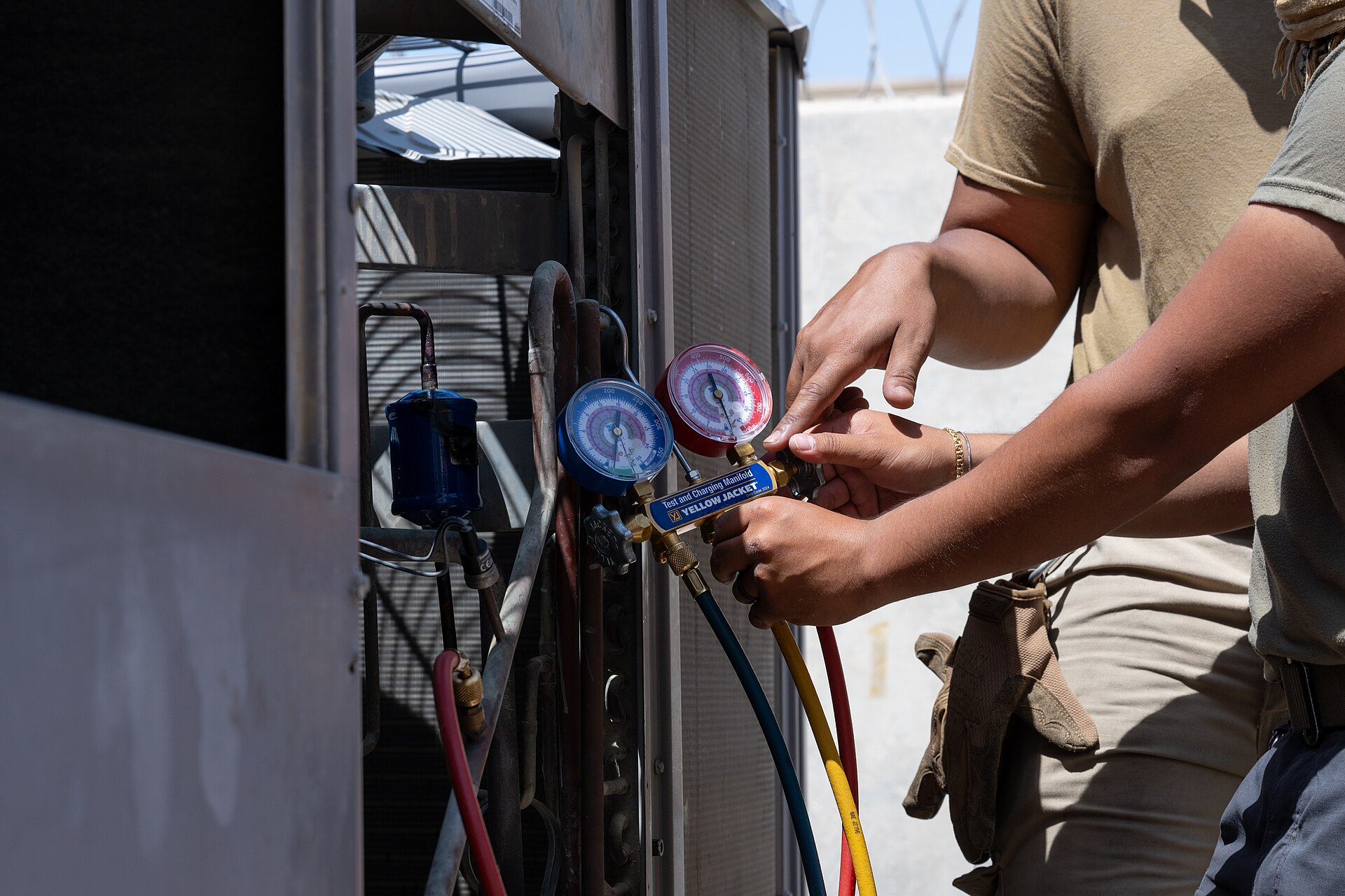 HVAC technicians checking an air-conditioning system with a pressure gauge