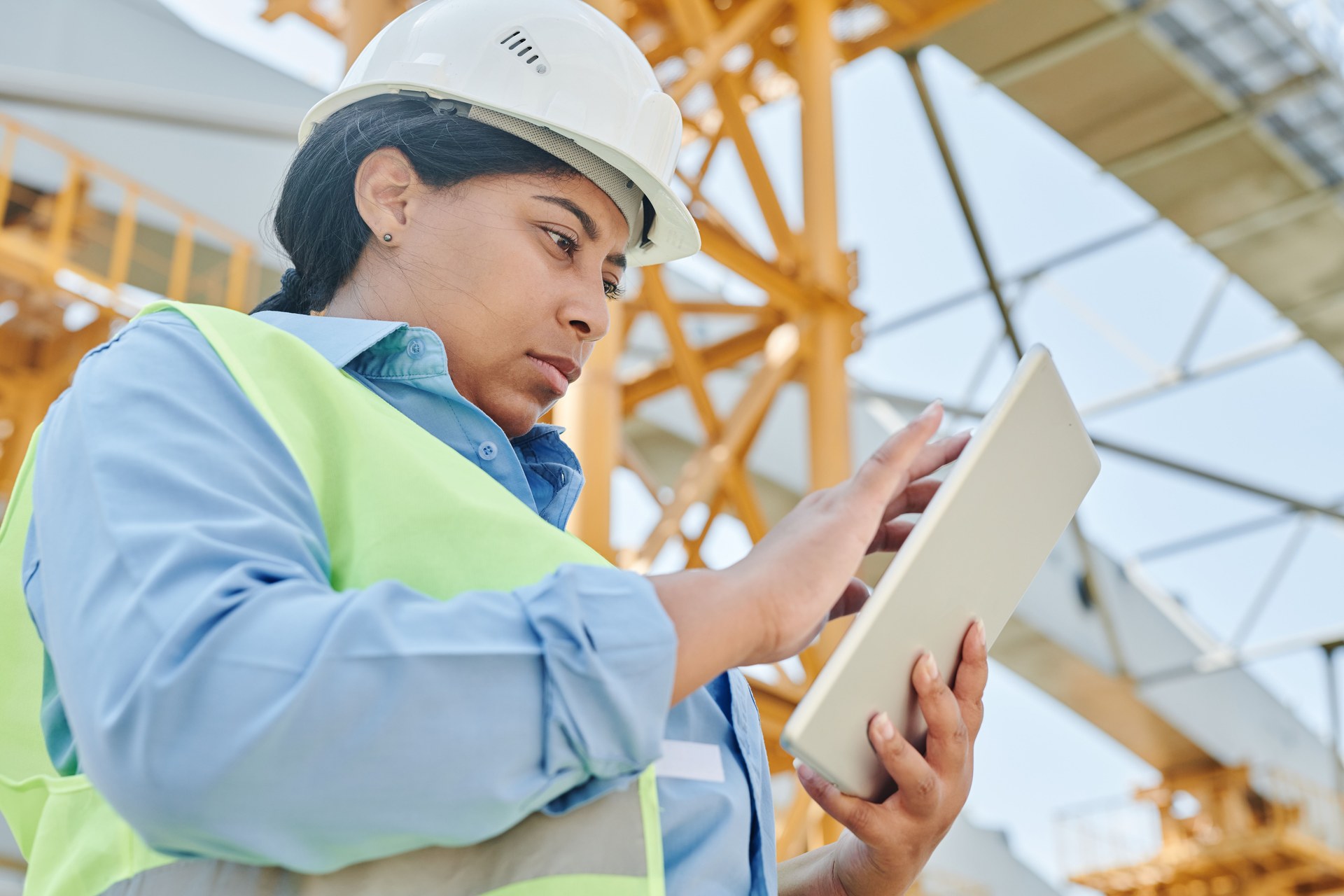 Field engineer in a hard hat holding a tablet at a jobsite